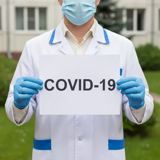 врач держит плакат с надписью COVID